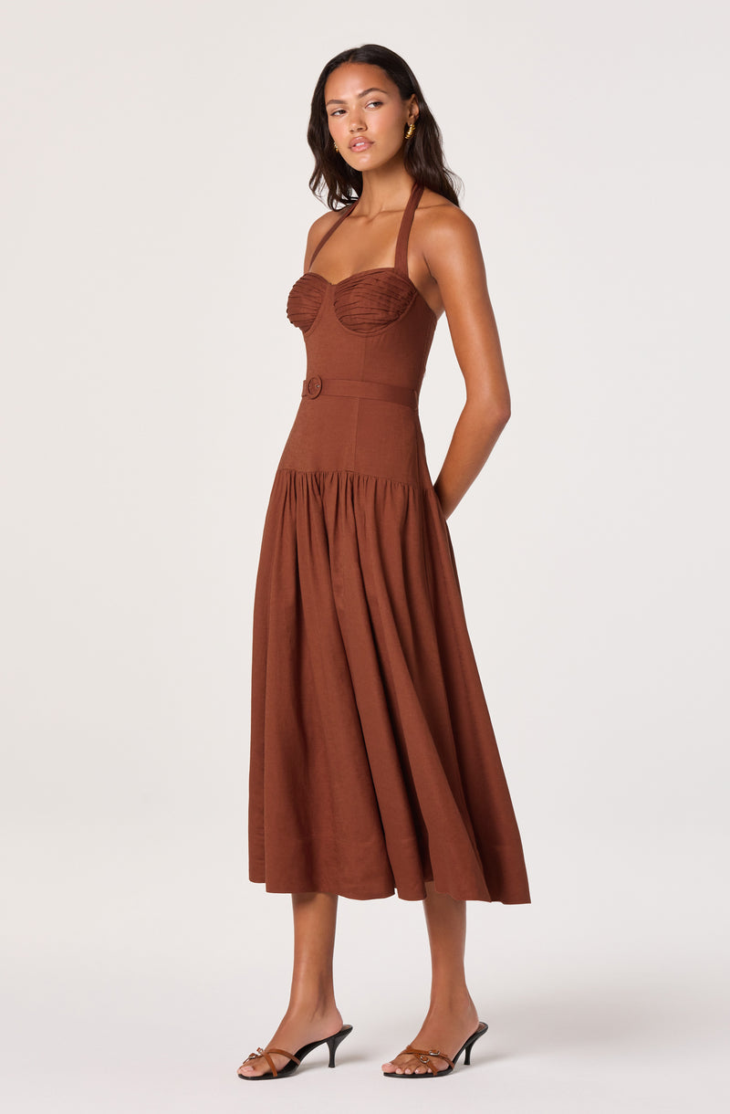 Woman wearing a brown sleeveless dress with a fitted bodice, empire waist, and full skirt.