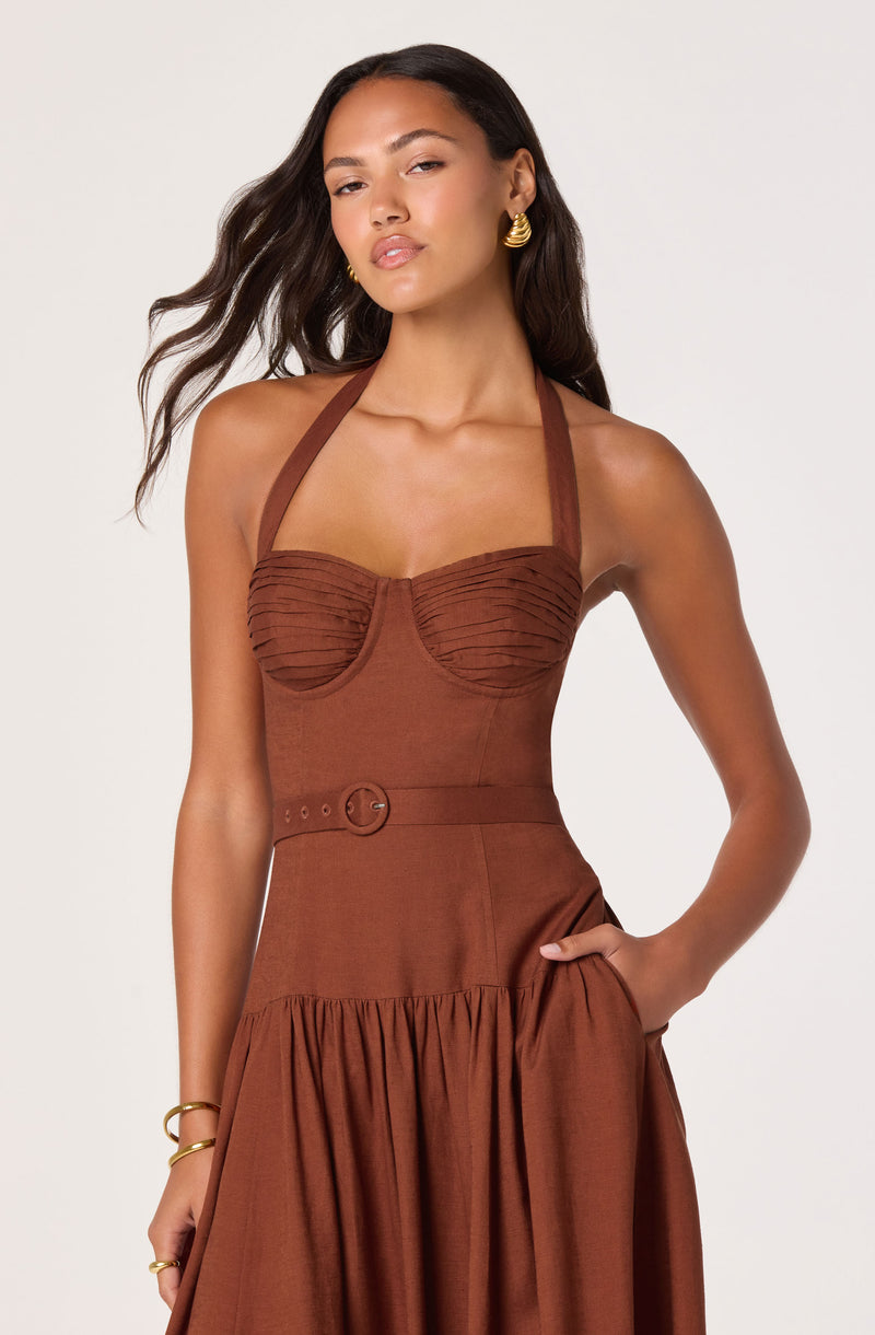 Woman in a sleeveless, rust-colored dress with a halter neckline, ruched bust, and gathered skirt.