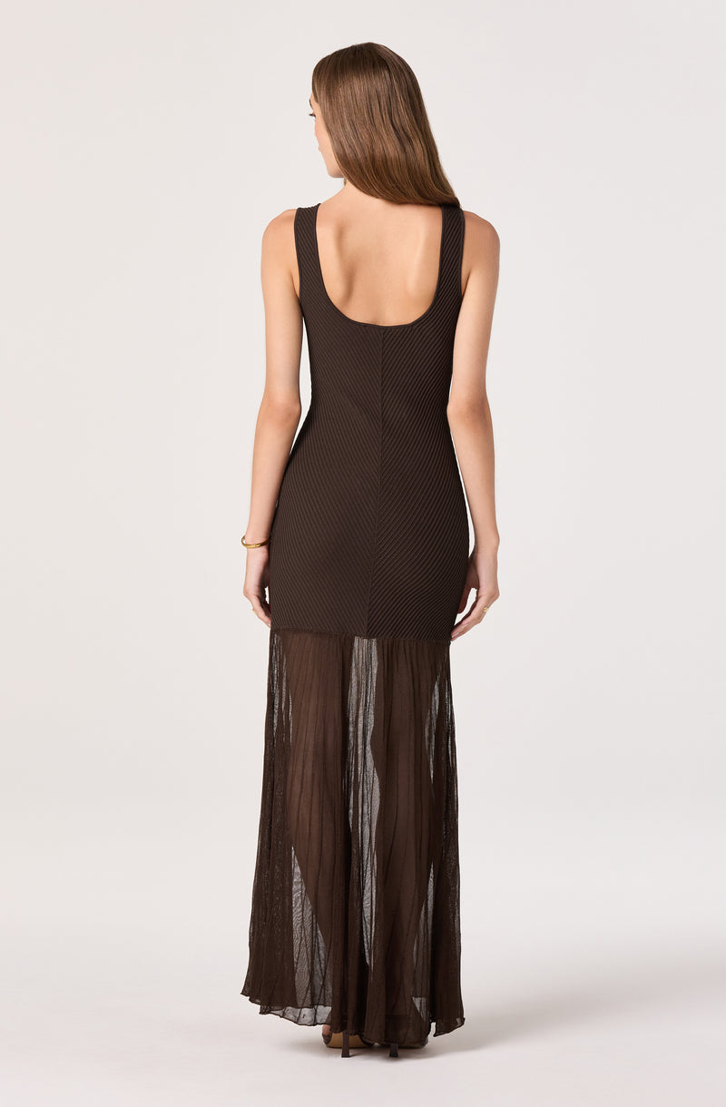 Woman in a black sleeveless layered dress with sheer, pleated fabric at the bottom.