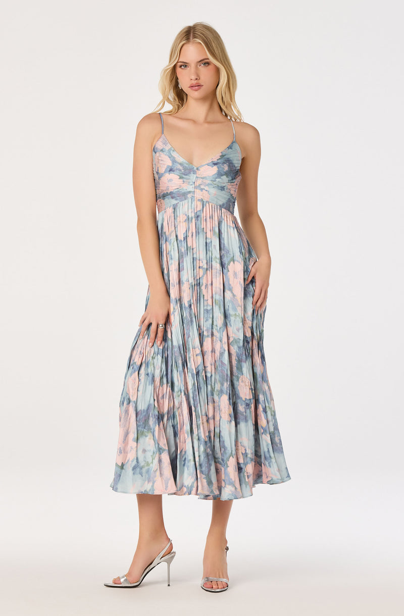 Woman in a pastel floral pleated maxi dress with spaghetti straps and open-toe heels.