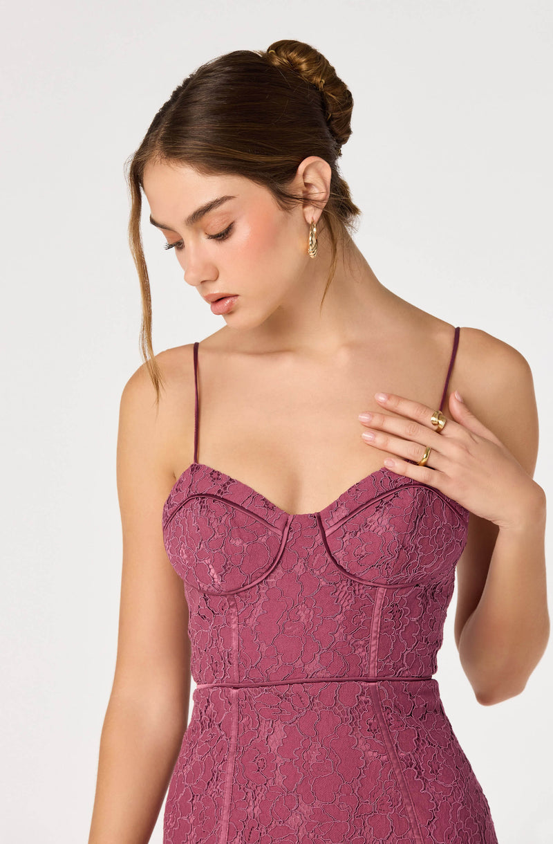 Woman wearing a pink lace dress with thin spaghetti straps.