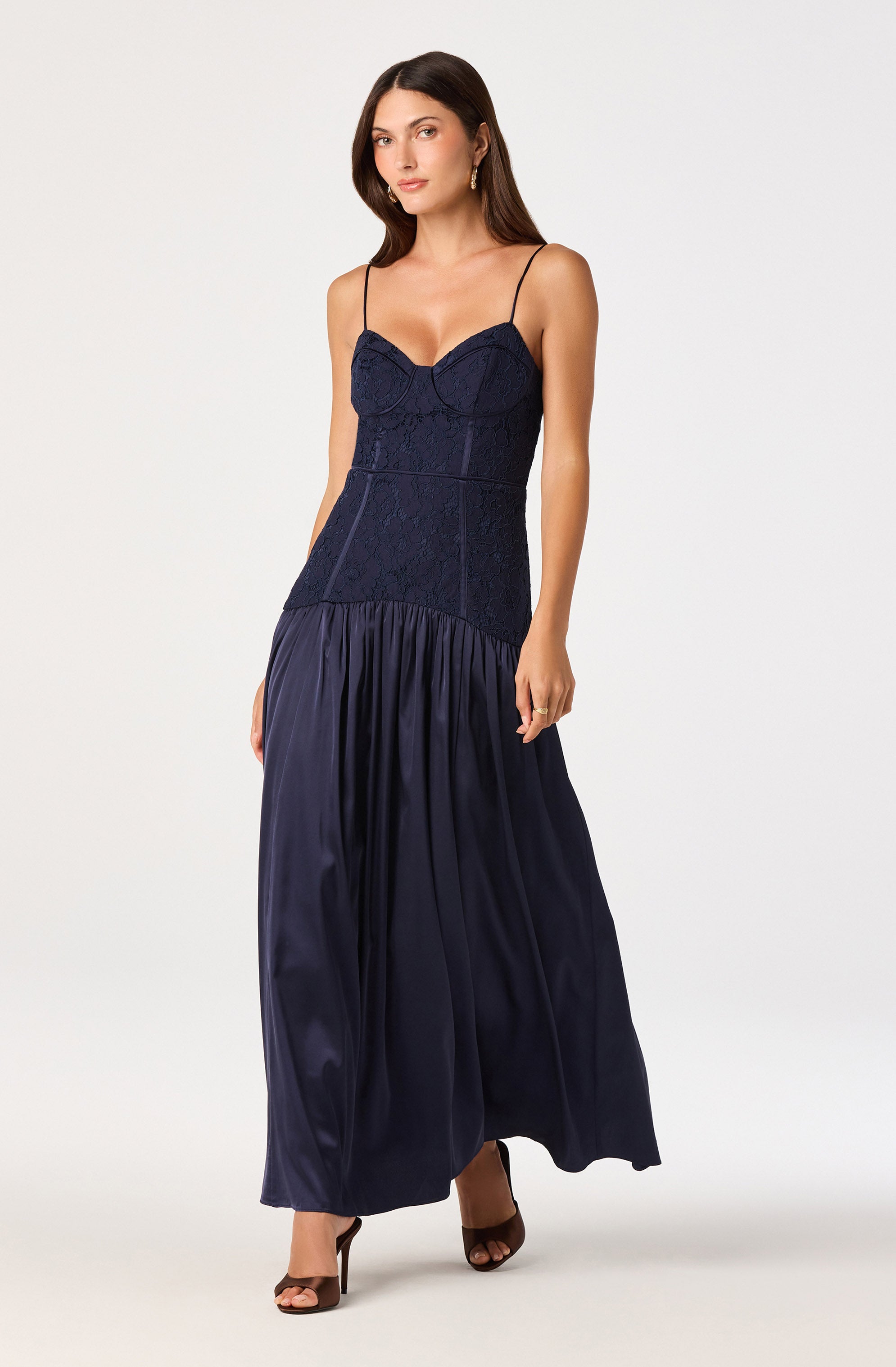 Woman wearing a navy blue, lace and satin maxi dress with spaghetti straps.