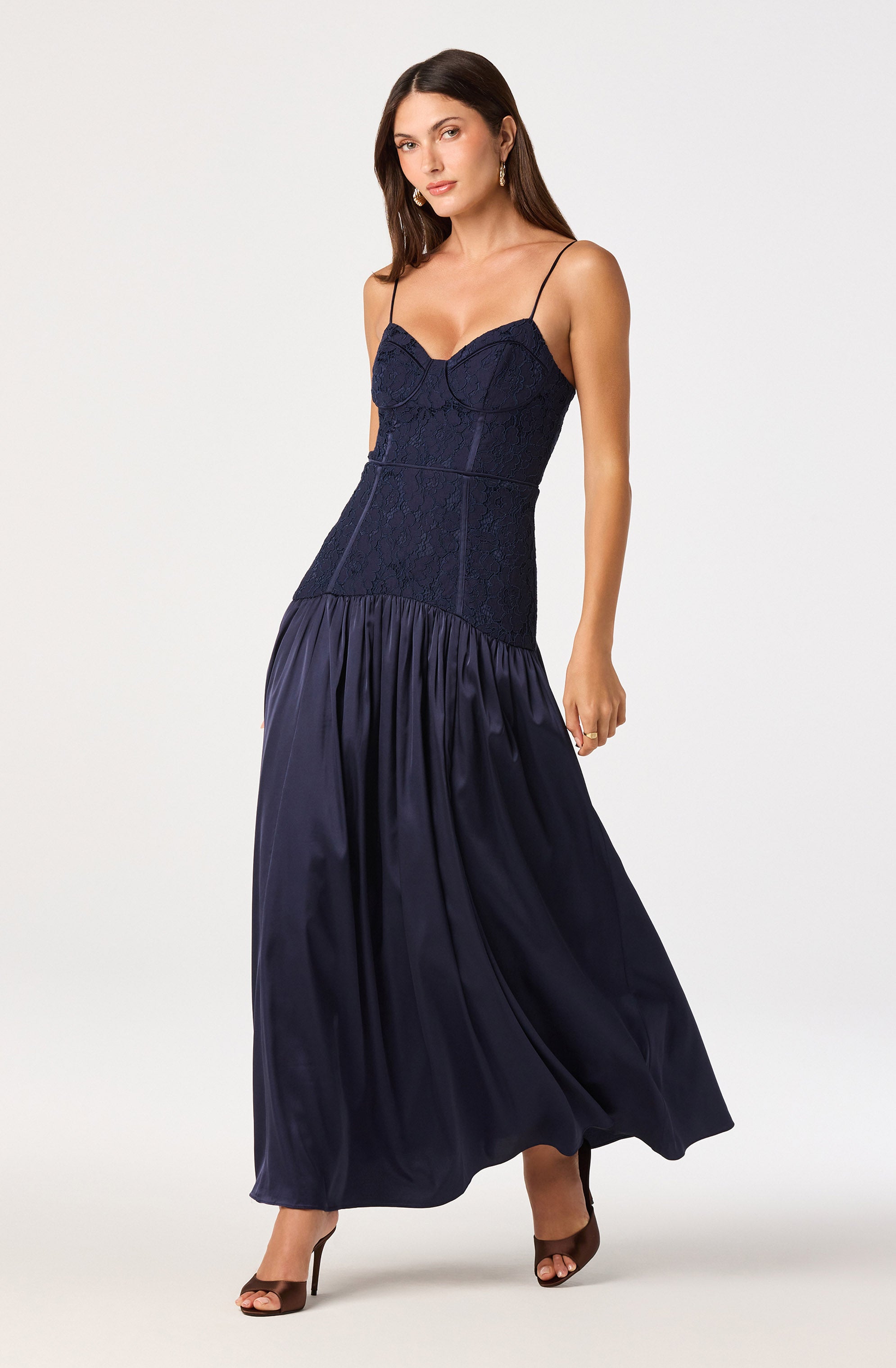 Woman in a navy blue spaghetti strap lace top and a long, flowing satin skirt.