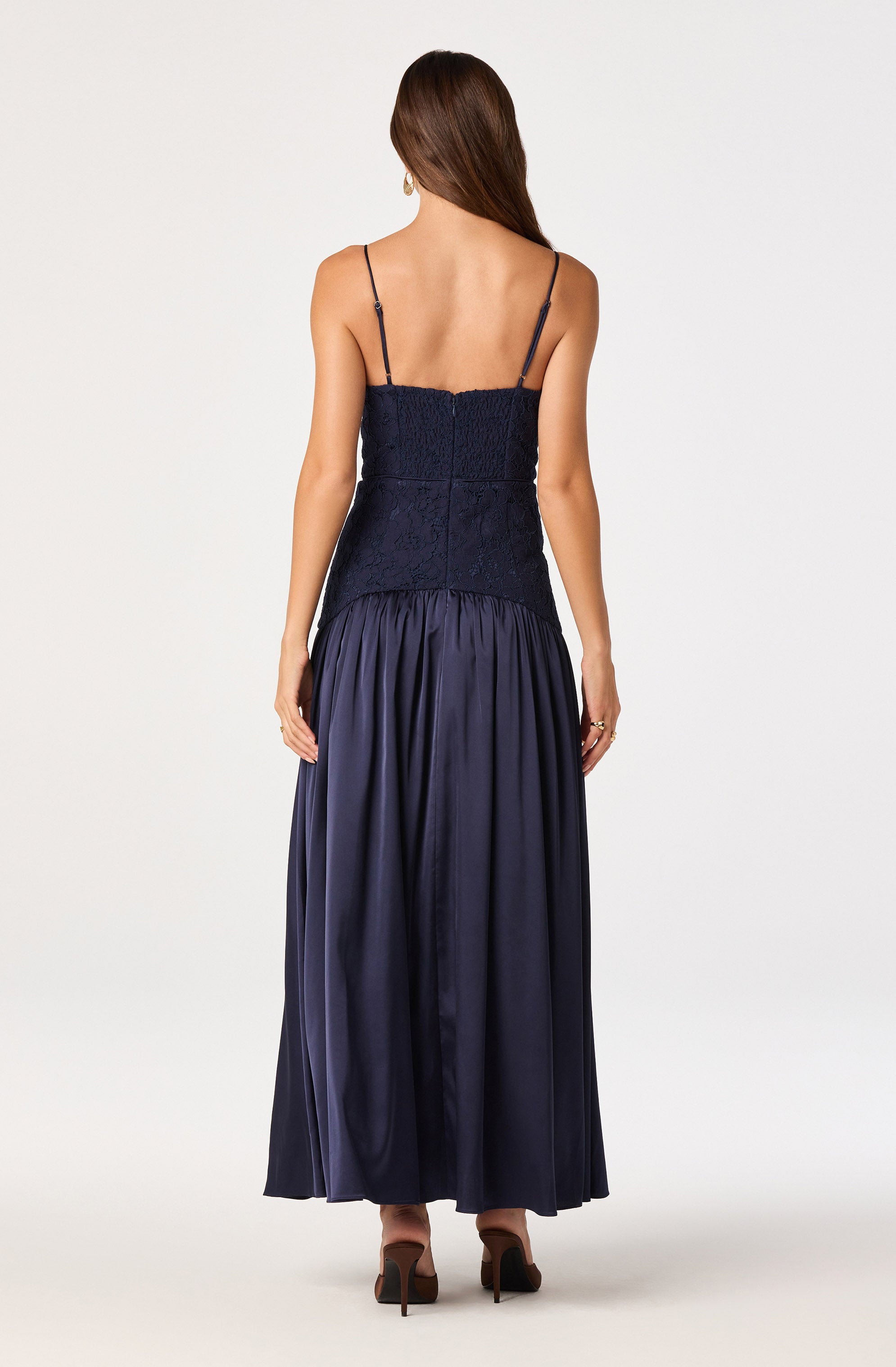 Woman in navy dress with薄 spaghetti straps, fitted lace bodice, and full satin skirt.
