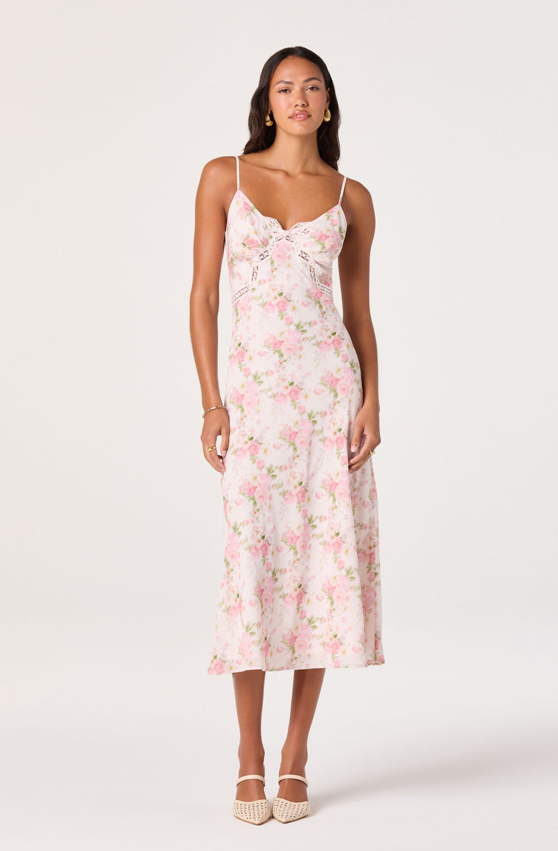Woman in a pink floral slip dress with thin straps, midi length, and beige heels.