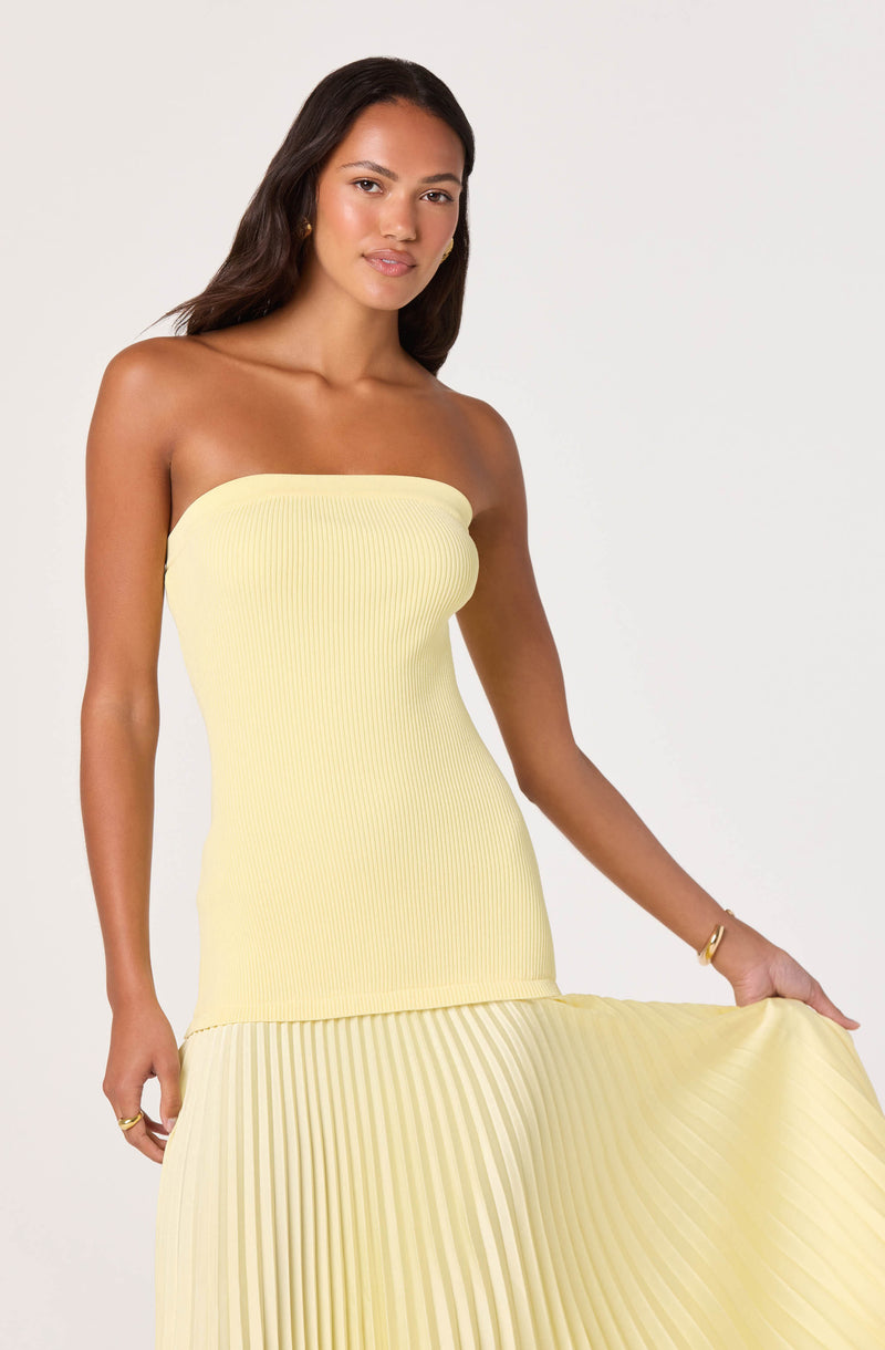 Woman in a strapless yellow pleated dress with a fitted bodice and flowing skirt.