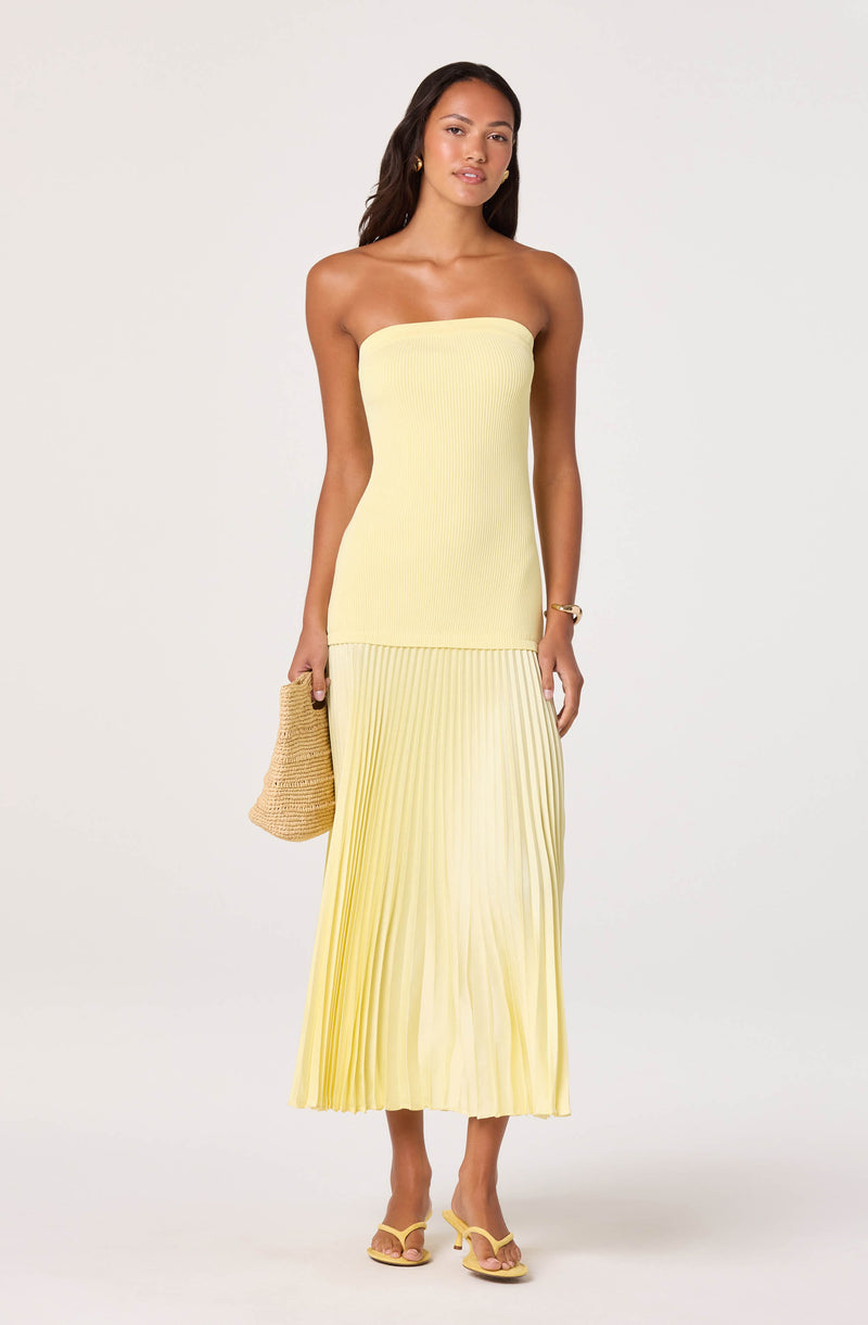 Light yellow strapless dress with a fitted top and pleated skirt, paired with yellow heels and a woven bag.