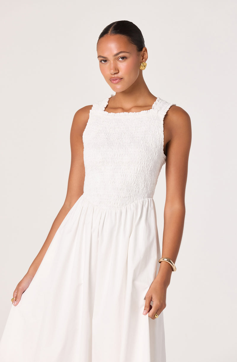 Woman wearing a sleeveless white dress with a textured bodice and flowing skirt.