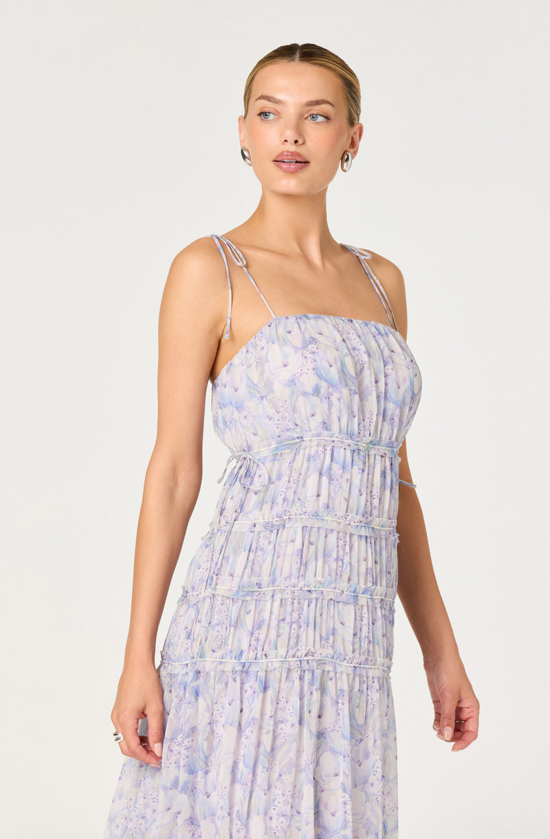 Woman wearing a light purple and white floral maxi dress with thin, double shoulder straps.