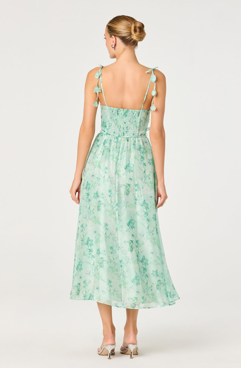 Light green floral maxi dress with tie straps and pom-pom details on shoulders.