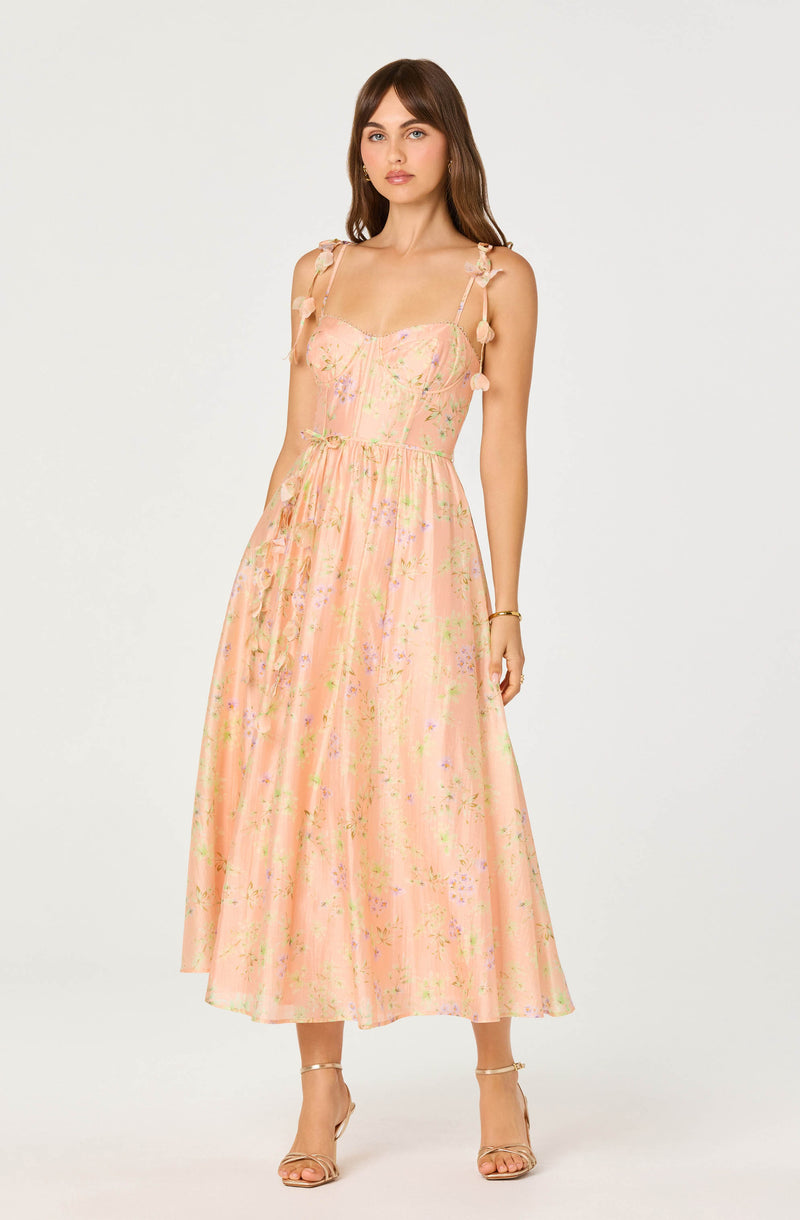 Pink floral dress with tie shoulder straps and pom-pom details.
