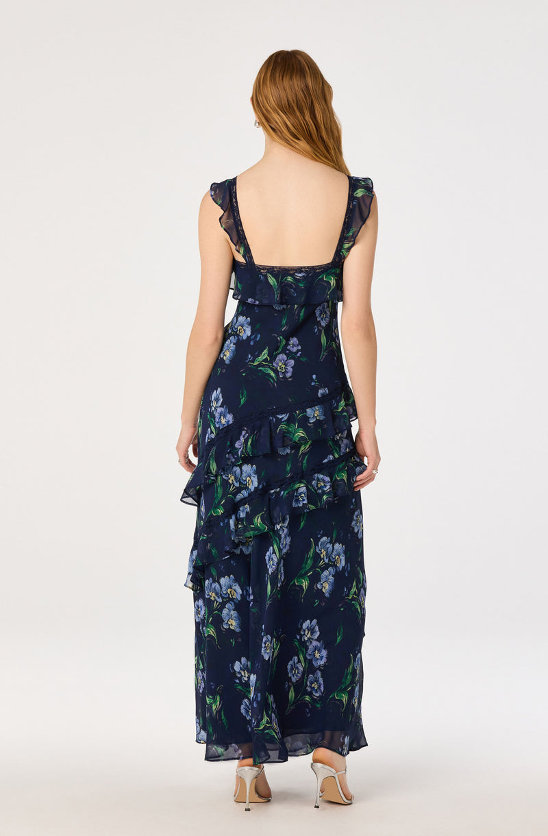 Woman in a navy floral dress with ruffled straps and tiered ruffles down the back.