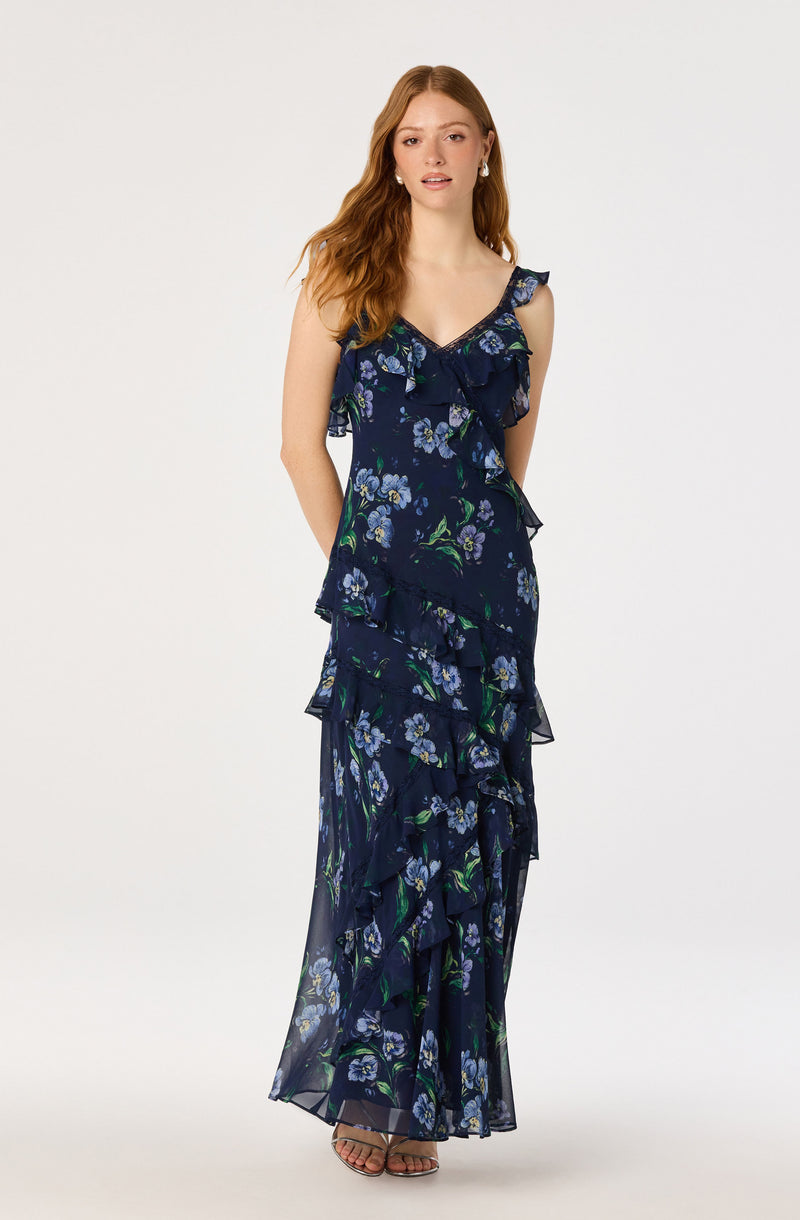 Woman in a long navy blue floral dress with ruffles and thin straps.