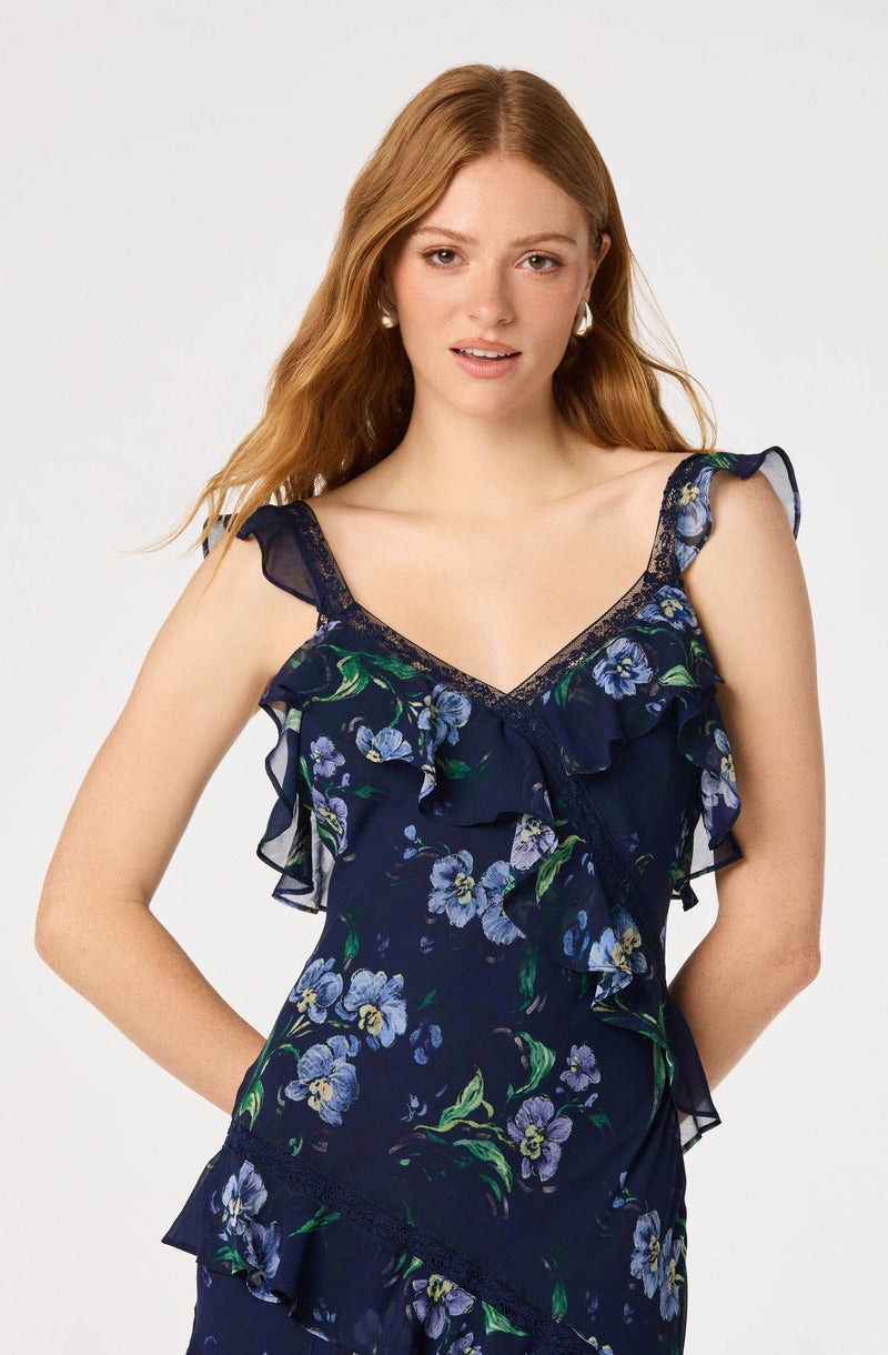 Woman wearing a navy blue floral sleeveless dress with ruffles and lace details.