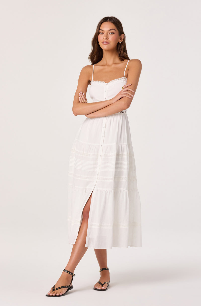 Woman in a white sundress with spaghetti straps and button-front, paired with black studded sandals.
