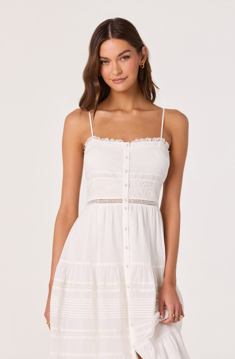 Woman in a white, sleeveless, button-front dress with lace and crochet details.