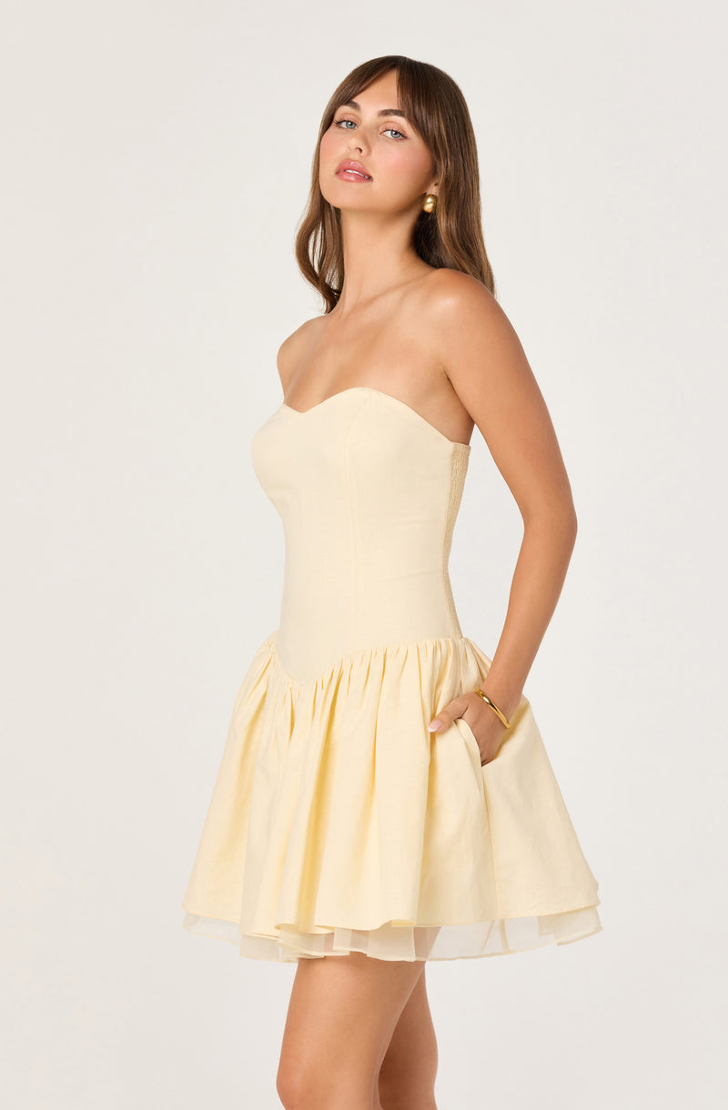 Women in a strapless cream dress with a fitted bodice and a gathered, flared skirt.