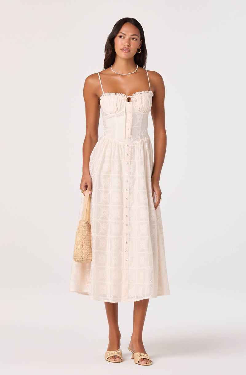 Woman wearing a cream-colored dress with thin straps, button-down front, and lace details.