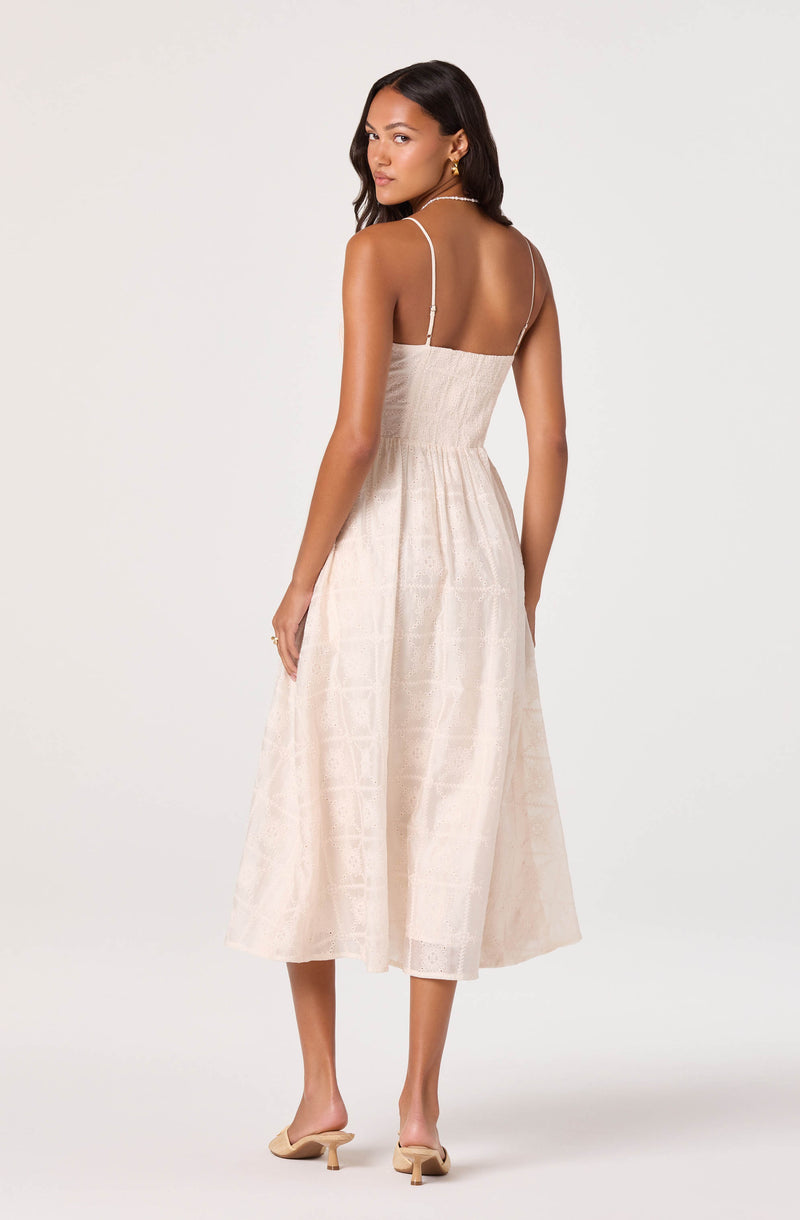 Women in cream-colored, sleeveless midi dress with spaghetti straps and a subtle pattern.