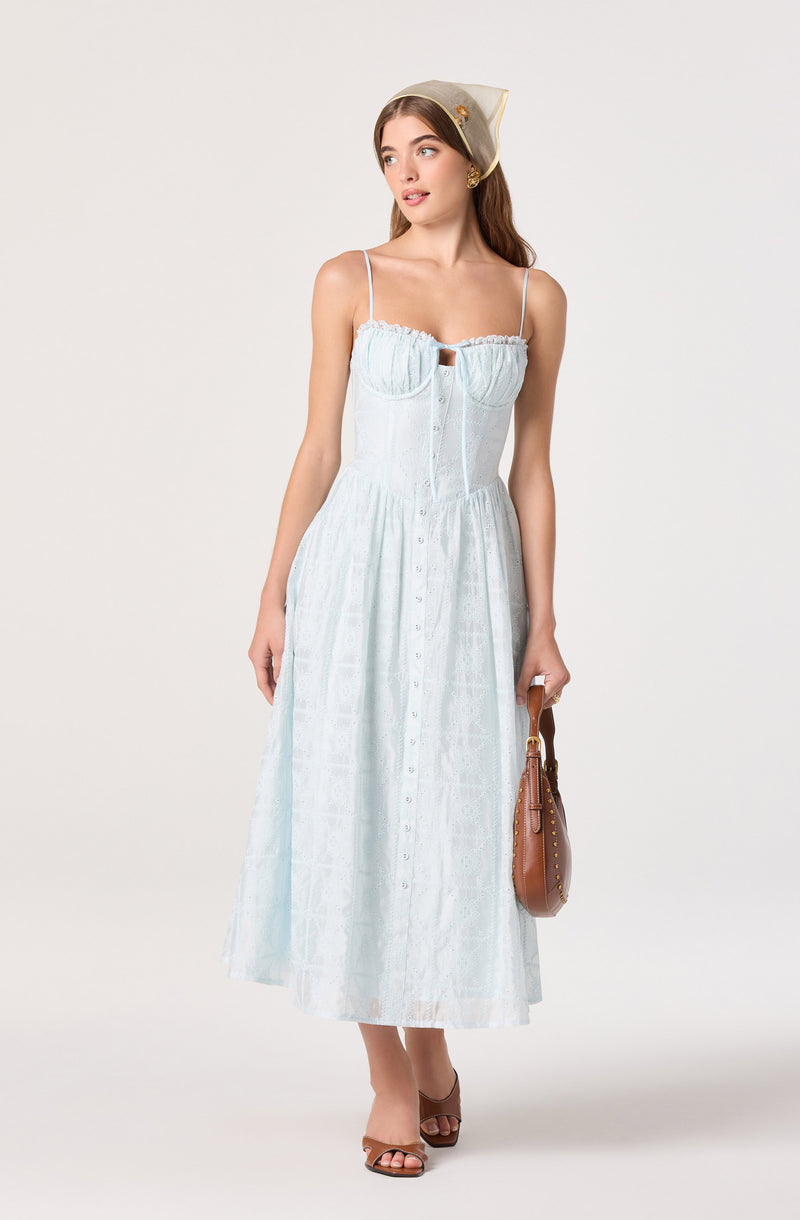 Woman wearing a light blue, sleeveless, button-down, ankle-length dress with thin spaghetti straps.