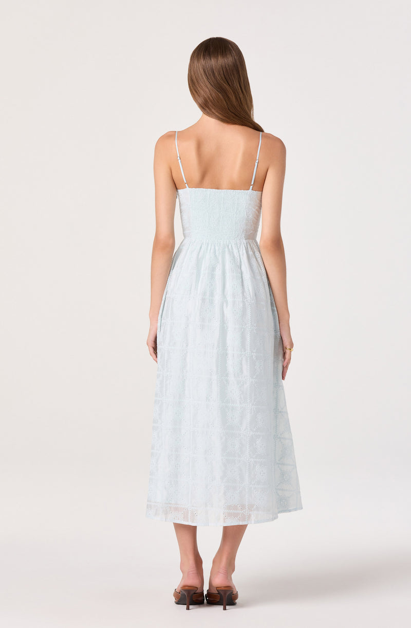 Woman in a white, sleeveless, spaghetti strap maxi dress with a smocked waistband.