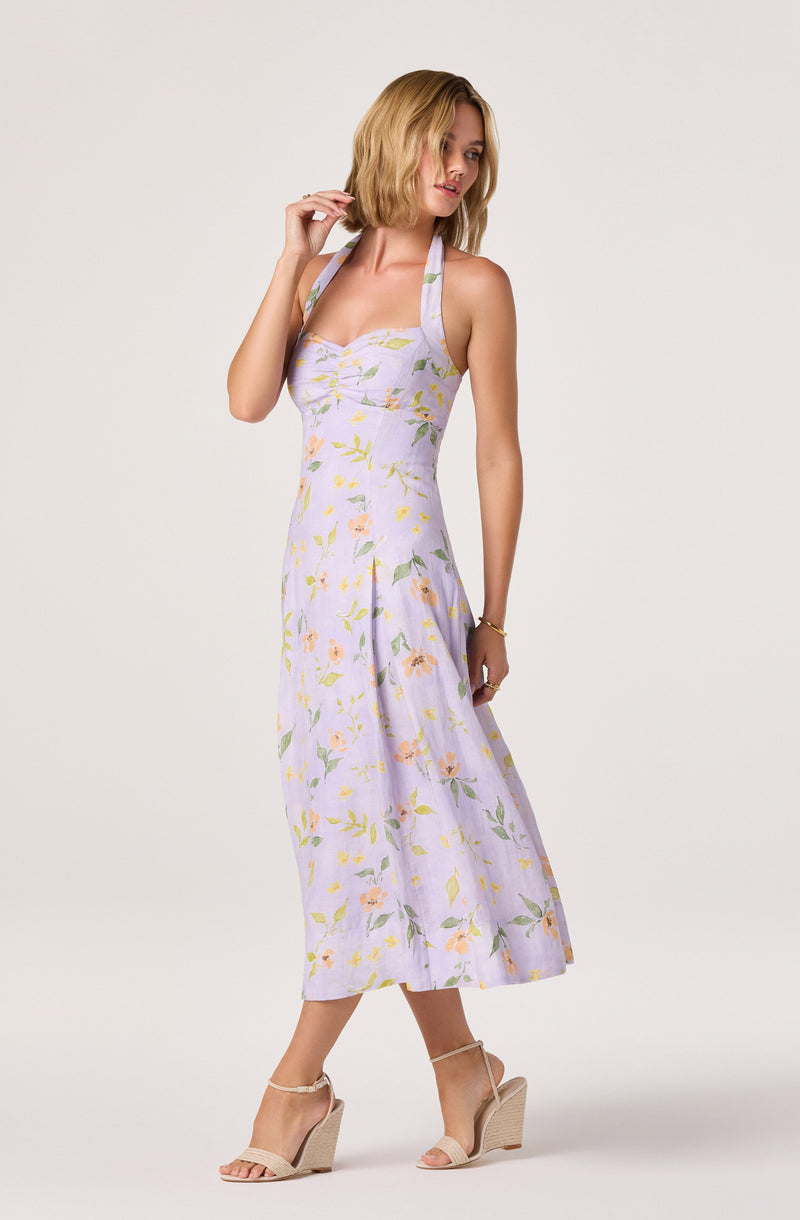 Woman wearing a light purple floral midi dress with a sweetheart neckline and wide straps.