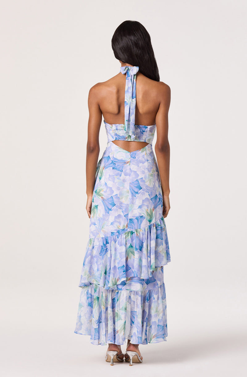 Back view of a woman in a blue floral halter top and matching tiered skirt.