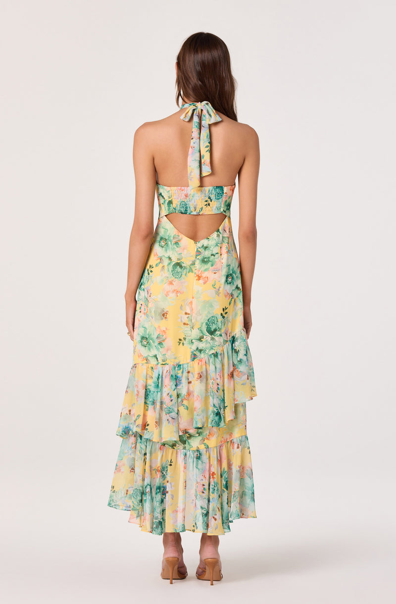 Back view of a woman in a colorful, floral halter dress with cutouts and ruffled tiers.
