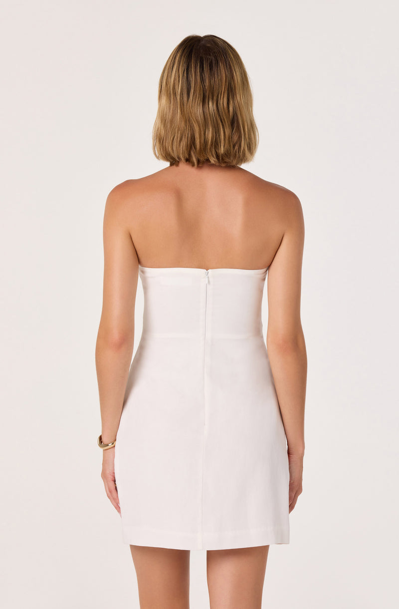 Back view of a woman wearing a strapless, white, knee-length dress with a center zipper.