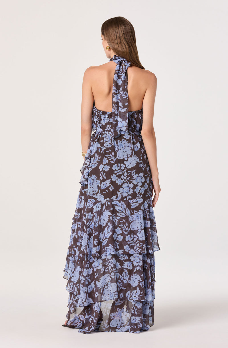 Back view of a woman wearing a strapless, floral-patterned maxi dress with a halter tie.