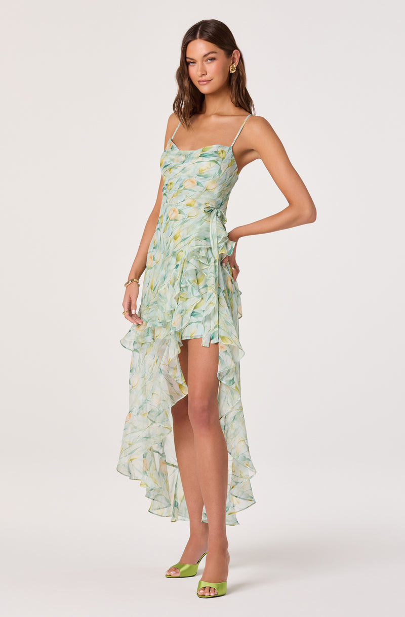 Woman wearing a light, pastel-colored, floral print dress with ruffles and thin straps.