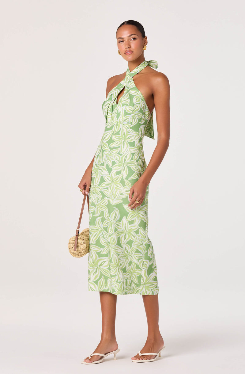 Woman in a green and white floral halter maxi dress with a tie at the neck.