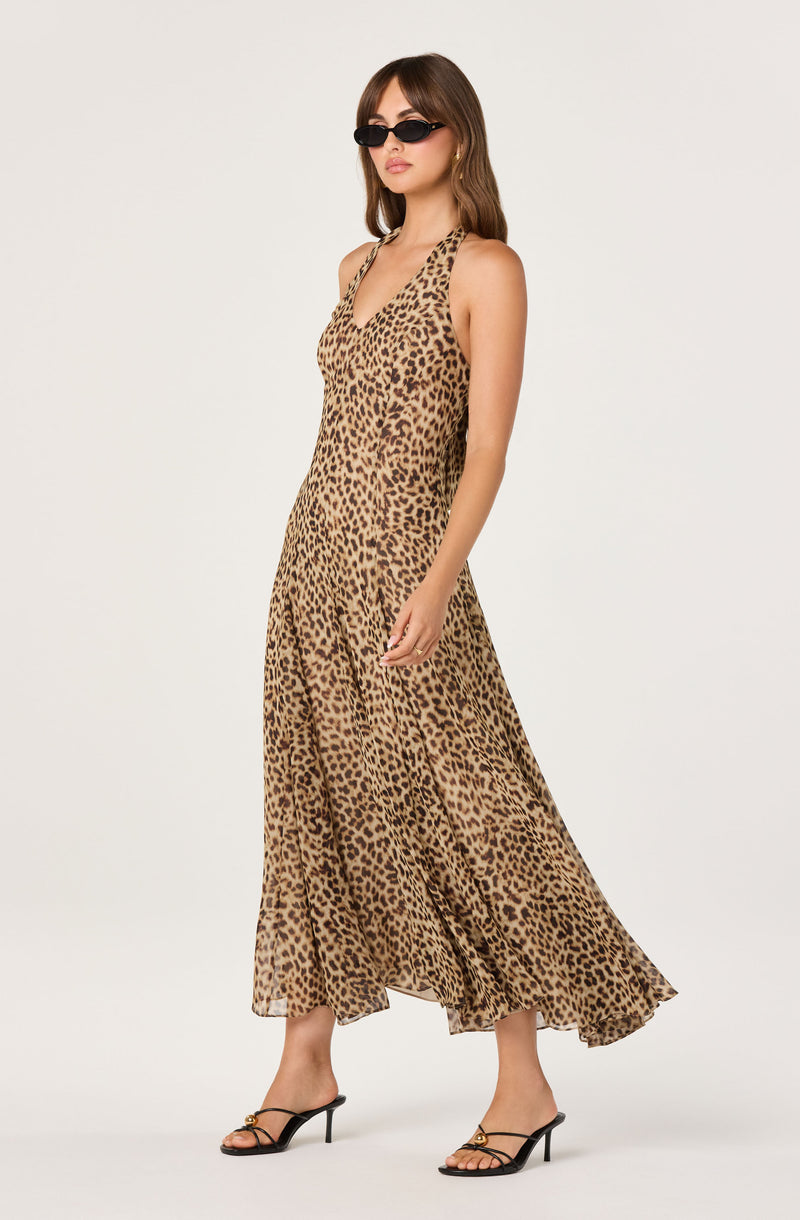 Leopard print sleeveless maxi dress, v-neck, flowing hem, paired with black heeled sandals and sunglasses.