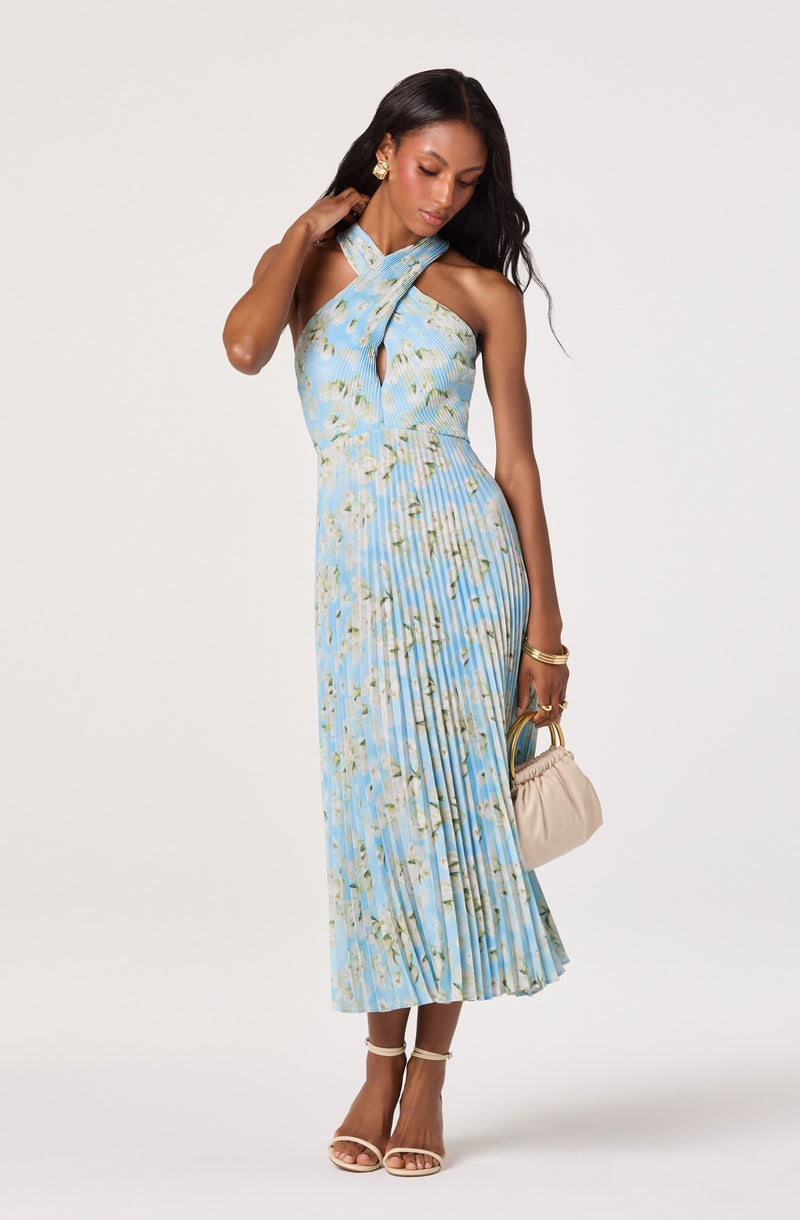 Woman wearing a light blue, floral-patterned, pleated halter dress with a keyhole neckline.