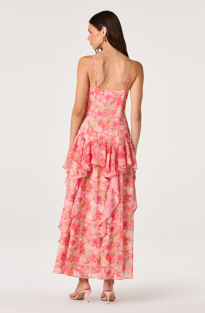 Woman in a pink floral dress with ruffles, thin straps, and a tiered skirt, wearing nude heels.