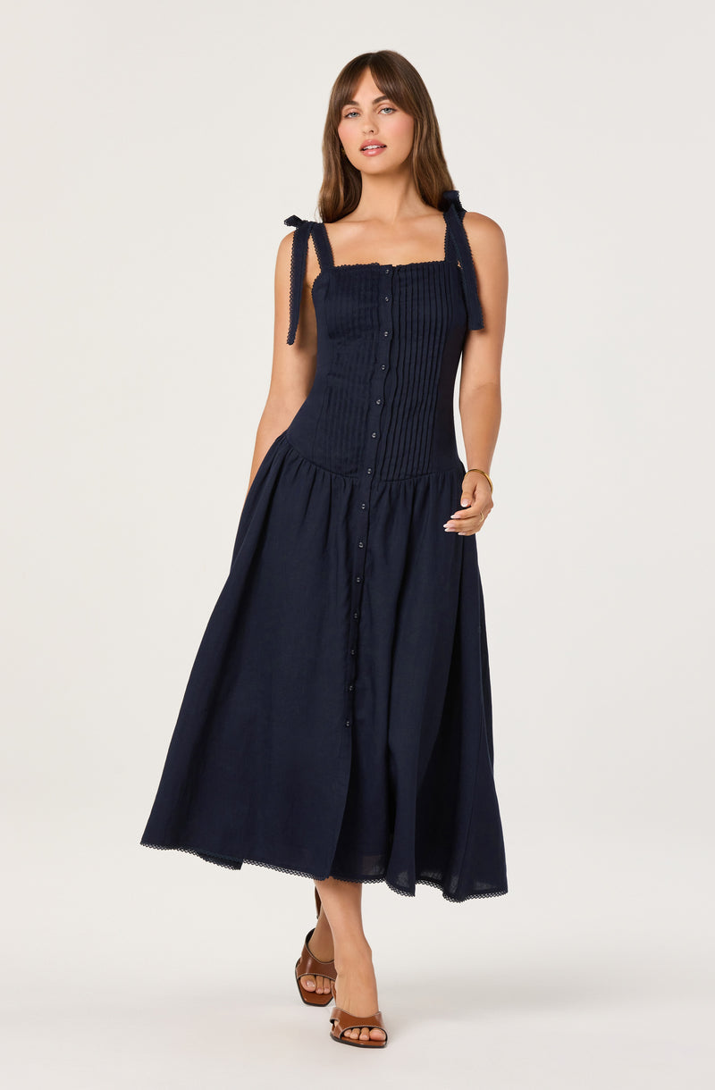 Girl in navy blue sleeveless dress with tied shoulder straps and button-down skirt.