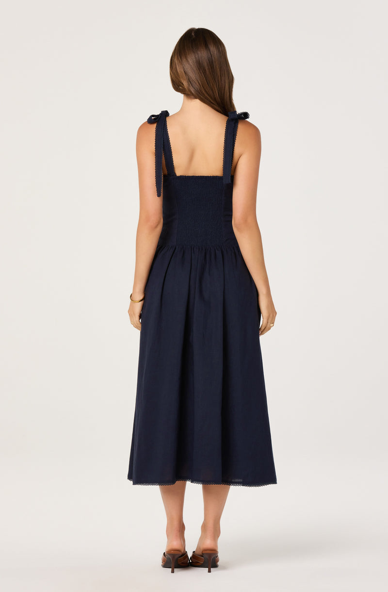 Navy blue sleeveless dress with bow-tied shoulder straps and a full-length, gathered skirt.
