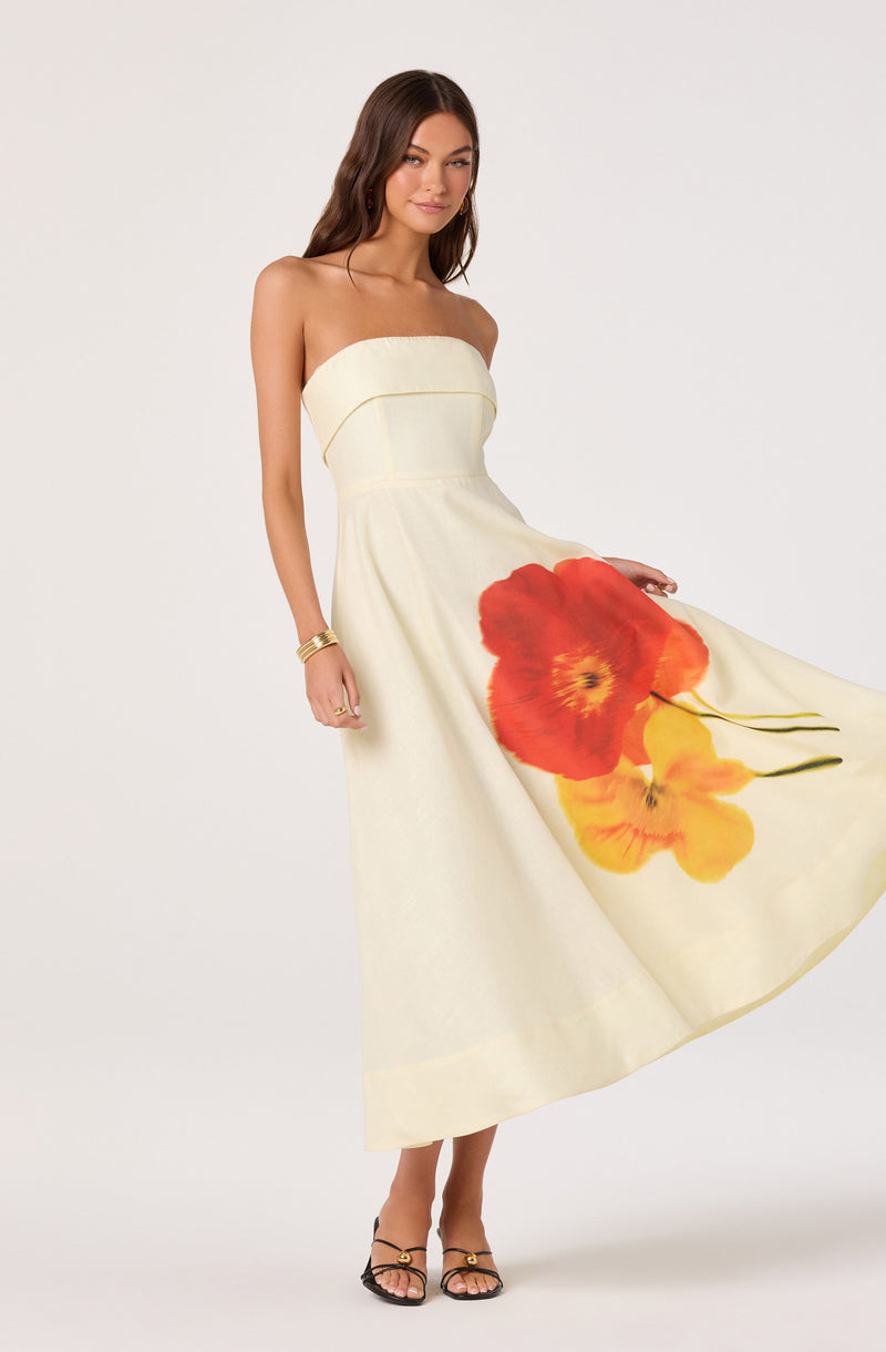 Cream strapless dress with large red and yellow floral print on the skirt.