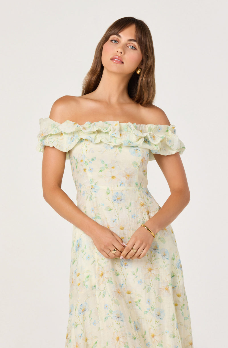 Woman in off-shoulder dress with ruffled neckline, floral pattern, pastel colors.