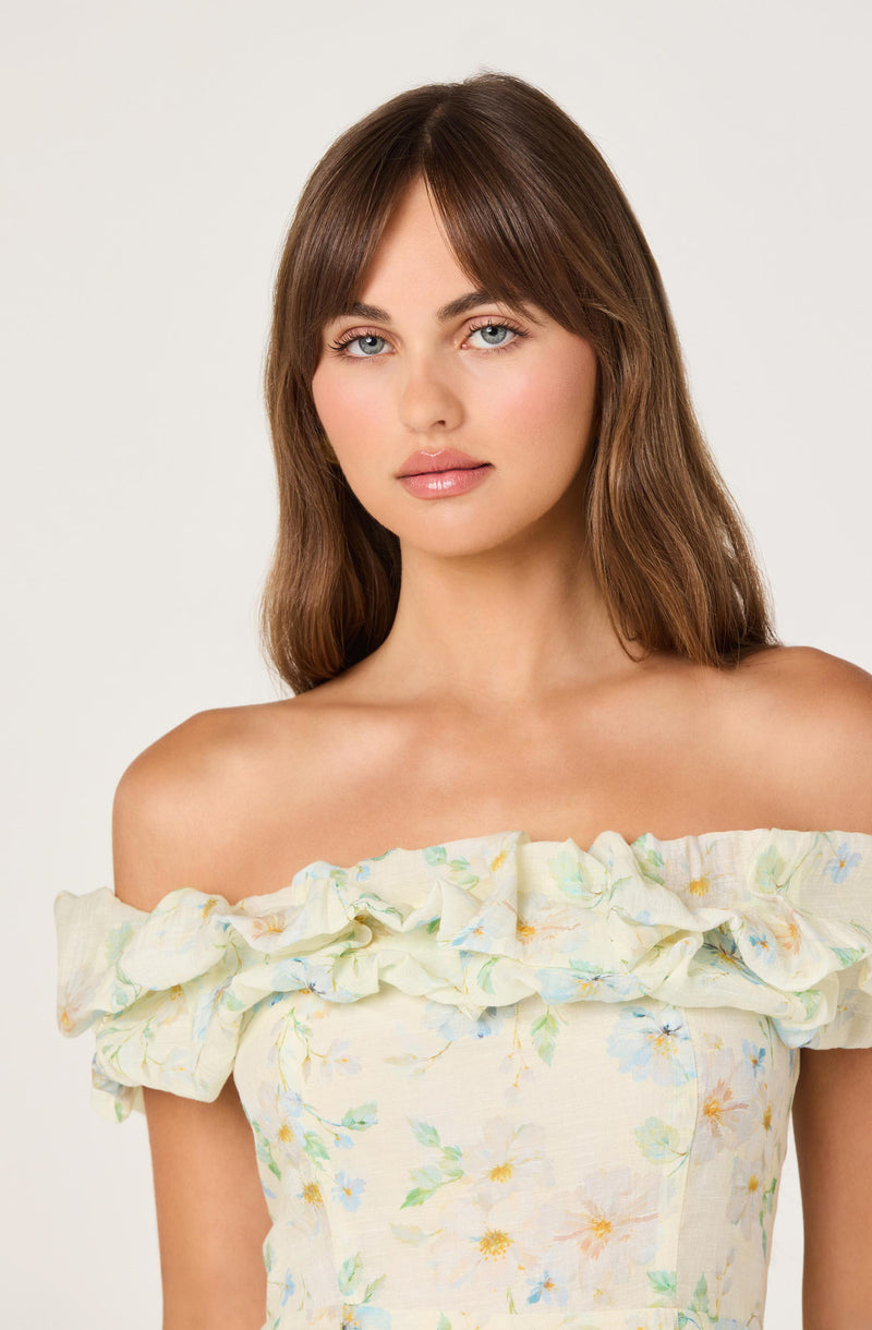 Woman wearing an off-the-shoulder dress with ruffled floral top.