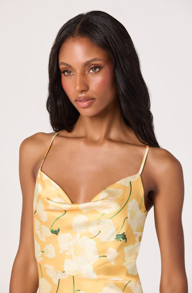 Woman wearing a yellow floral slip dress with thin spaghetti straps.