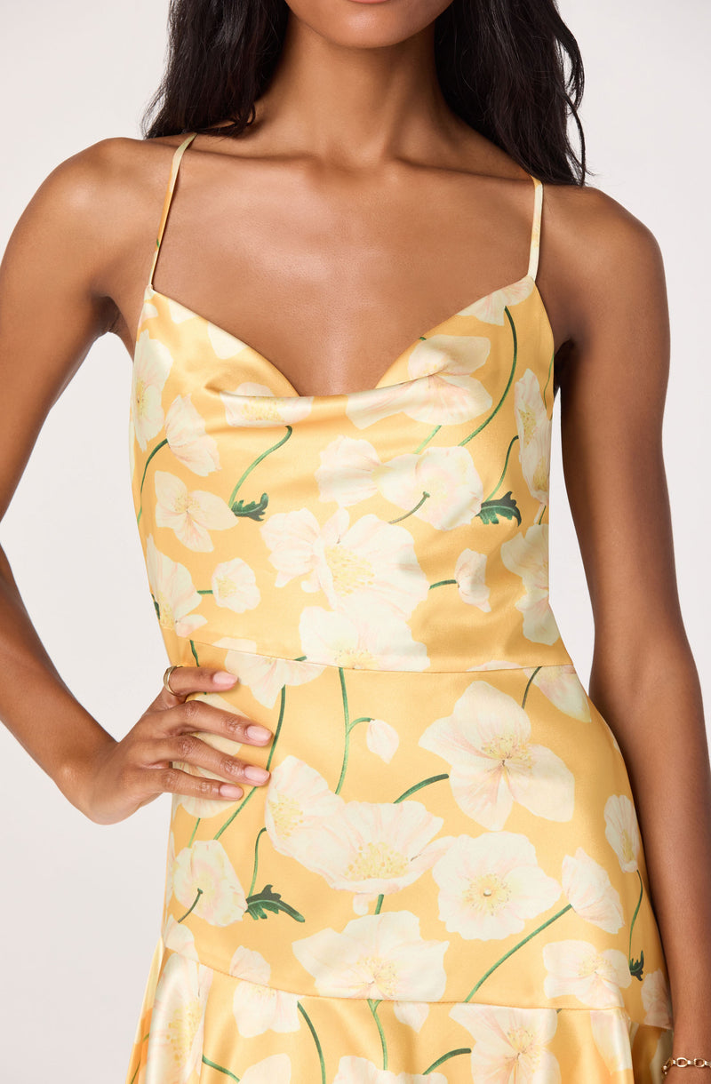 Woman wearing a yellow floral slip dress with spaghetti straps.
