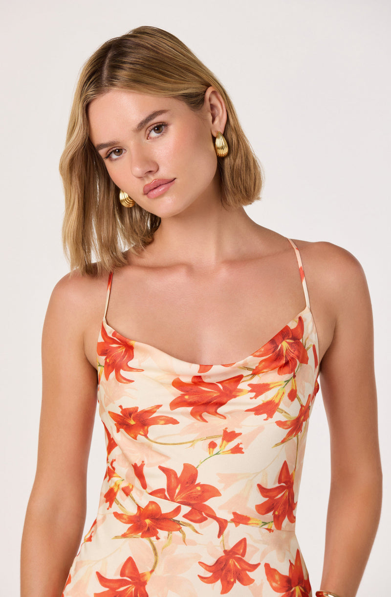 Woman wearing a cream-colored spaghetti strap dress with orange floral pattern.