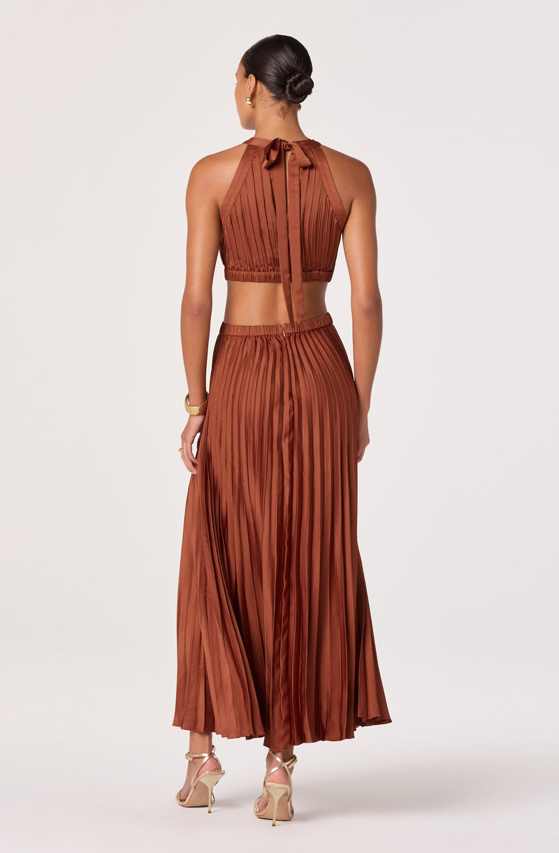Back view of a woman wearing a rust-colored, pleated, halter crop top and matching wide-leg pants.