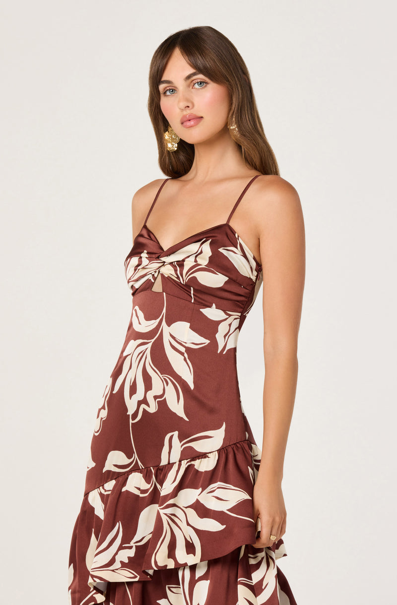 Woman wearing a brown dress with beige floral pattern, spaghetti straps, and ruffled hem.