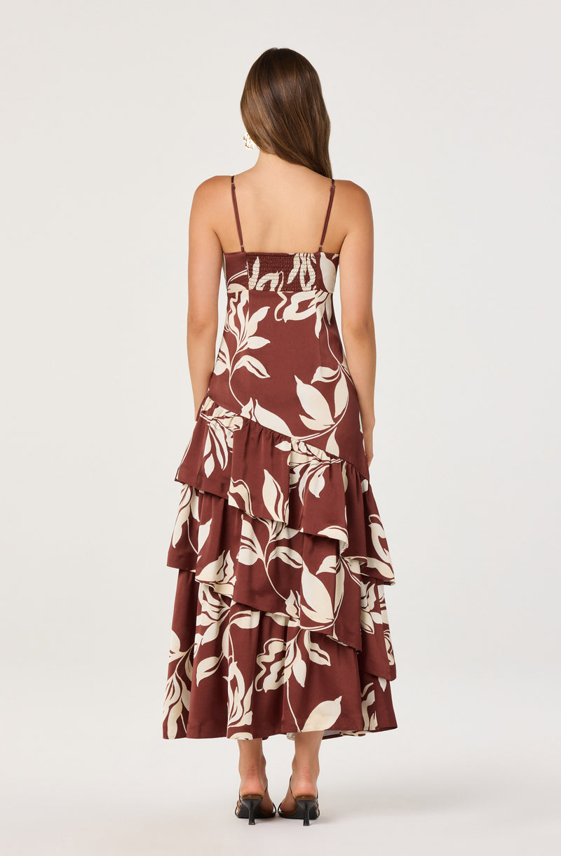 Woman in a sleeveless, spaghetti strap, floral print, tiered maxi dress in brown and cream.