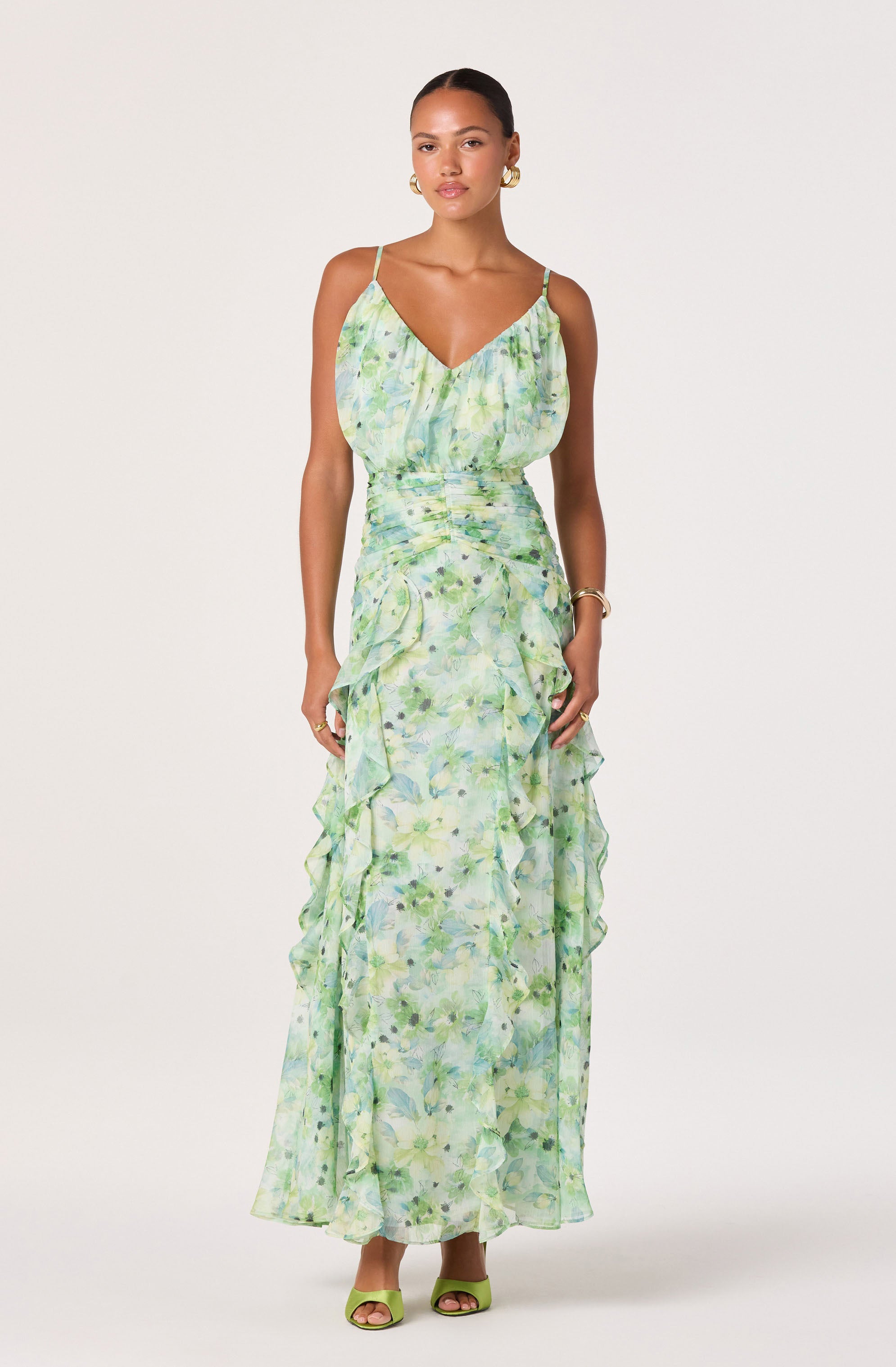 Woman in a light green, floral patterned sundress with spaghetti straps and ruffled details.
