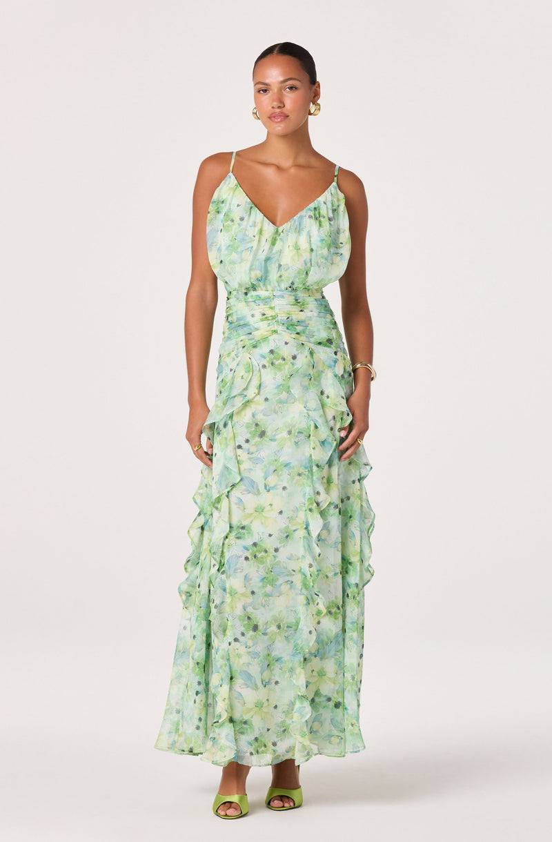 Woman in a light green, floral patterned sundress with spaghetti straps and ruffled details.