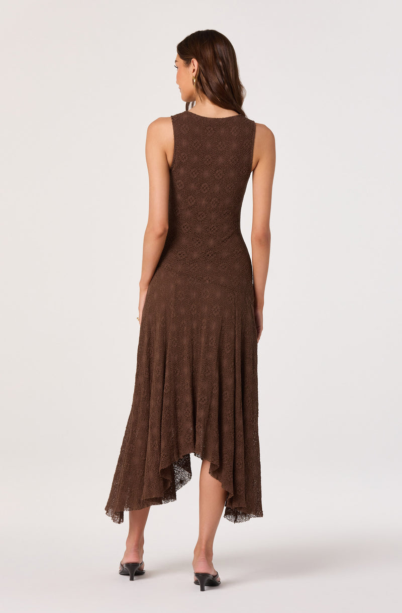 Woman wearing a sleeveless, brown textured dress with an asymmetrical hemline.