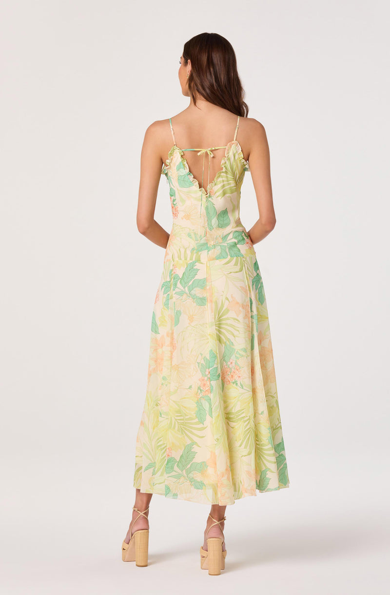 Woman in a pastel yellow and green floral dress with spaghetti straps and a back tie.